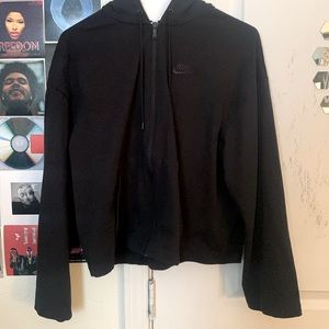 This is a black cropped jacket with a hoodie.